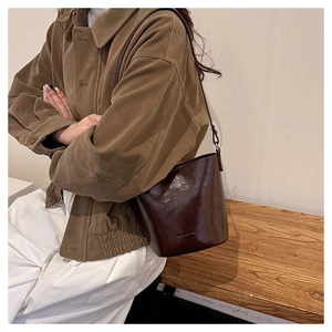 Detail of dark brown vintage leather bucket bag with glossy texture on a wooden bench