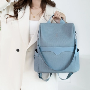 Detail of light blue backpack with twill texture and metal rabbit logo on white blazer