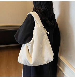 Close-up of white oversized tote bag showing wrinkled fabric texture and wide shoulder strap