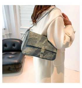 Gros plan d'un sac à bandoulière gris-vert rétro avec boucle métallique et fine lanière