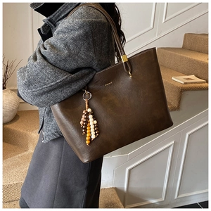 Détail d'un grand cabas vintage marron avec breloque en perles et finitions dorées
