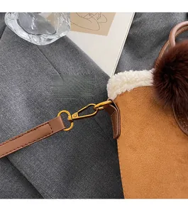 Détail de la quincaillerie en métal doré et du daim marron sur un sac seau élégant