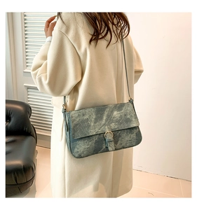 Détail du sac bandoulière en cuir bleu gris marbré avec boucle dorée sur le modèle