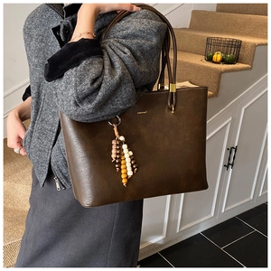 Détail du sac cabas marron foncé avec charme perlé rétro et finitions métalliques dorées