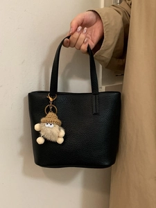 Minimalist black pebble leather bucket bag with a cute monster charm for women