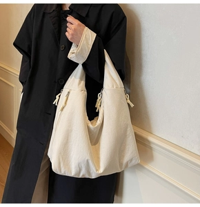 Detail of off-white oversized canvas tote bag with metal zipper pockets and knot decor