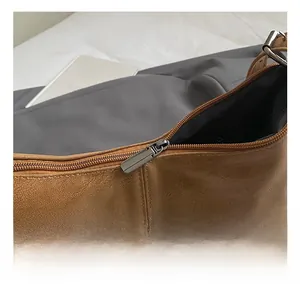 Detail of high-quality smooth metal zipper and lychee leather texture on brown shoulder bag