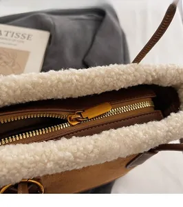 Détail de la fermeture éclair dorée et de la bordure en faux mouton blanc sur le sac brun