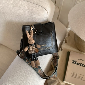 Detail of black pebbled leather bag with ethnic strap and a cute brown rabbit charm