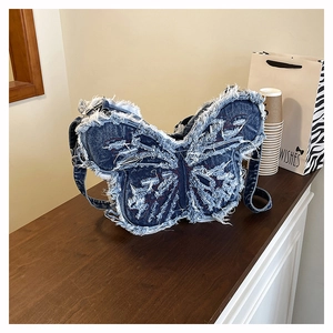 Dettaglio borsa a farfalla in denim blu con bordi sfilacciati e cuciture rosse