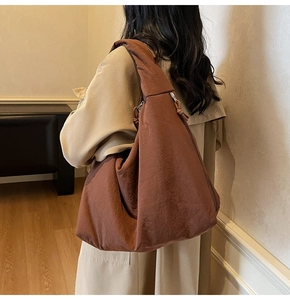 Brown large capacity tote bag shown on shoulder with soft lighting in cozy room