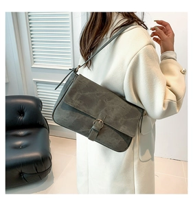 Détail du sac bandoulière en daim gris foncé avec une boucle métallique ronde élégante