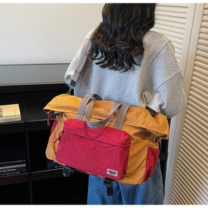 Vista dettagliata della borsa da viaggio senape e rossa indossata da un modello