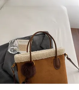Détail d'un sac à main en daim marron avec bordure en fausse fourrure et breloque