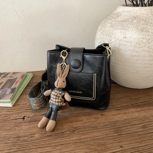 Detail of black vintage bucket bag featuring a bohemian strap and a cute rabbit charm