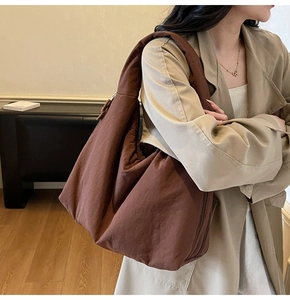 Detail of a large chocolate brown nylon tote bag shown from side with zip closure