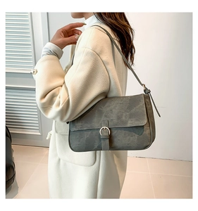 Détail d'un sac bandoulière rétro gris mat porté par un mannequin dans un décor épuré