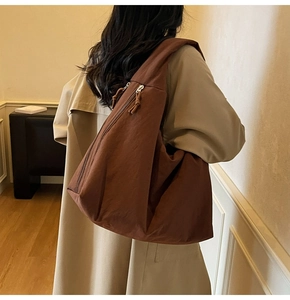 Detail view of large brown canvas tote bag with dual zippers and woven pulls