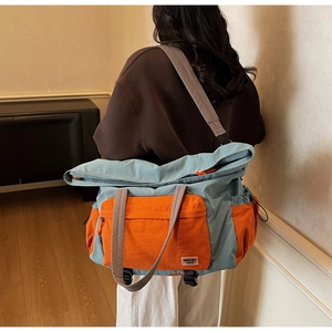 Dettaglio della grande borsa da viaggio in tela con pannelli blu e arancione a contrasto