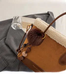 Détail du sac à main en daim marron avec bordure en peau lainée et breloques en fourrure