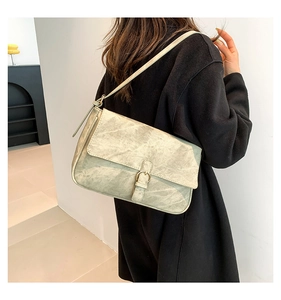 Détail du sac à bandoulière vintage vert sauge en cuir avec boucle sur un modèle en manteau