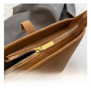 Detailed macro view of golden metal zipper and brown suede texture on bucket bag