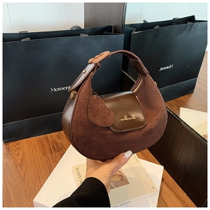 Detail of a dark brown half-moon hobo bag featuring mixed suede and smooth leather textures