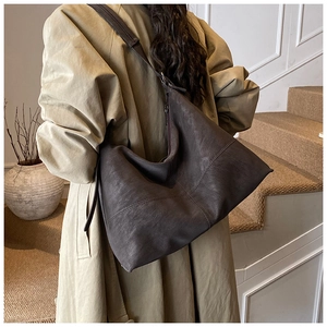 Detailed texture of dark brown vintage faux leather tote bag worn with a classic trench coat