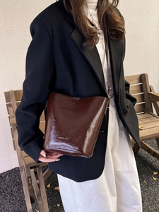 Vintage dark brown waxed leather bucket bag shown on a model in a classic outdoor setting