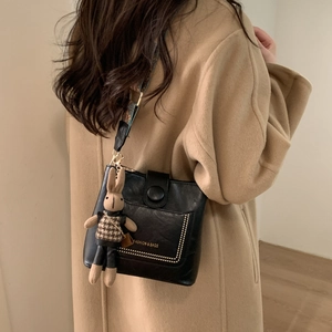 Detail of black pebbled leather crossbody bag with ethnic strap and rabbit charm