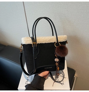 Détail du sac à main en daim noir avec garniture en fausse fourrure blanche et doré mat