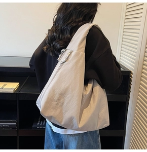 Rear view of a spacious beige tote bag on model showing shoulder strap and fabric texture