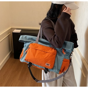 Dettaglio della borsa da viaggio in nylon blu e arancione con tracolla e tasca frontale