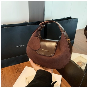 Detailed macro view of retro brown suede handbag with golden logo and heart charm accessory