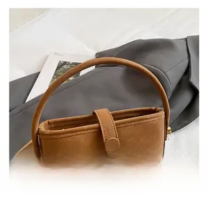 Detail of brown suede bucket bag featuring vintage gold metal buckle and smooth handle