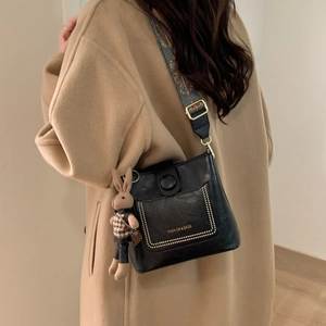 Detail of black leather crossbody bag featuring an ethnic strap and a cute rabbit charm