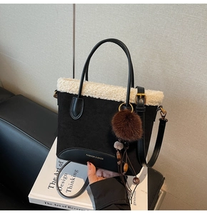 Détail du sac noir en similicuir avec bordure en fausse fourrure blanche et pompon