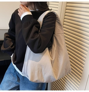 Side view of large light grey tote bag with wide strap on model for office commute