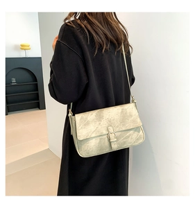 Gros plan d'un sac à bandoulière vert clair texturé avec boucle en métal sur un modèle