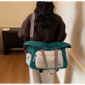 Dettaglio della grande borsa da viaggio verde acqua e grigia indossata a spalla