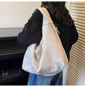 Detail view of light grey tote bag with side zipper and drawstring on a wide strap