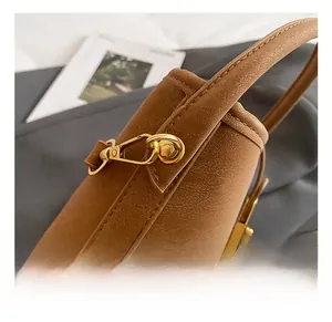 Close-up of golden metal hook and fine stitching on a premium brown leather handbag