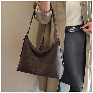 Macro detail of dark brown hobo bag with retro leather texture and cross stitching