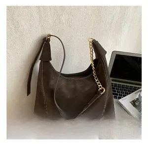 Detailed macro view of dark brown suede hobo bag with white stitching and gold chain strap