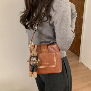 Detail of brown faux leather shoulder bag with ethnic woven strap and cute bunny charm
