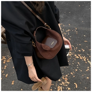 Macro view of retro brown crescent leather bag with gold embossed logo and autumn street scene