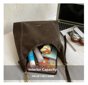 Spacious interior of dark brown suede hobo bag showing tablet, books and cosmetics