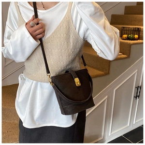 Detail der dunkelbraunen Wildleder-Eimertasche mit Goldverschluss und Handgriff