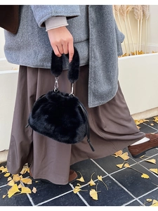 Détail du sac seau noir en fausse fourrure avec cordon et poignée en peluche douce