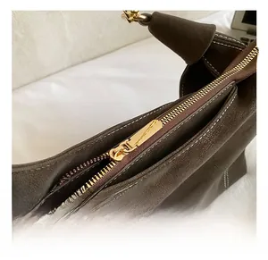 Macro detail of the dark brown suede bag featuring premium gold zipper and fine white stitching